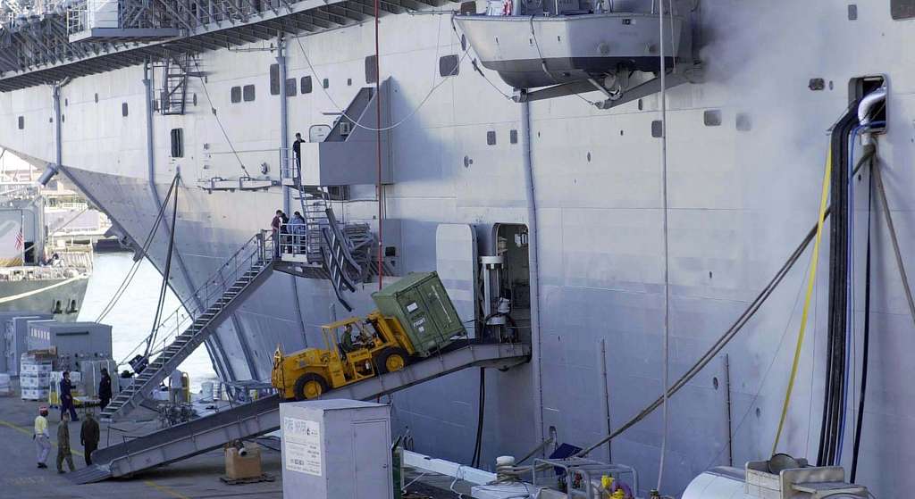 A forklift carries cargo into the amphibious assault ship USS Nassau ...