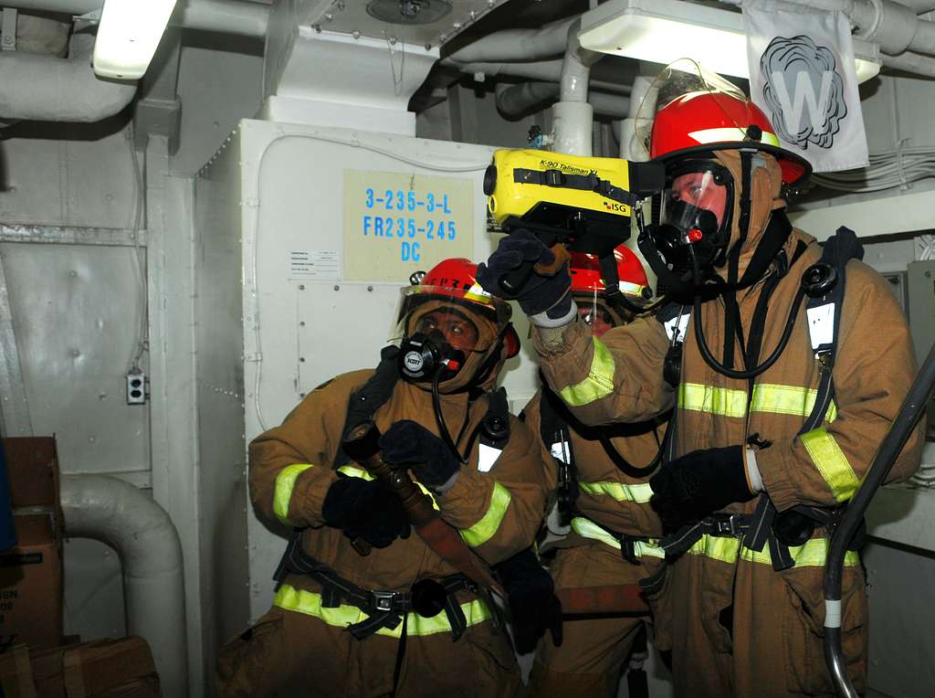 Sailors simulate scanning for a fire during a damage control drill ...